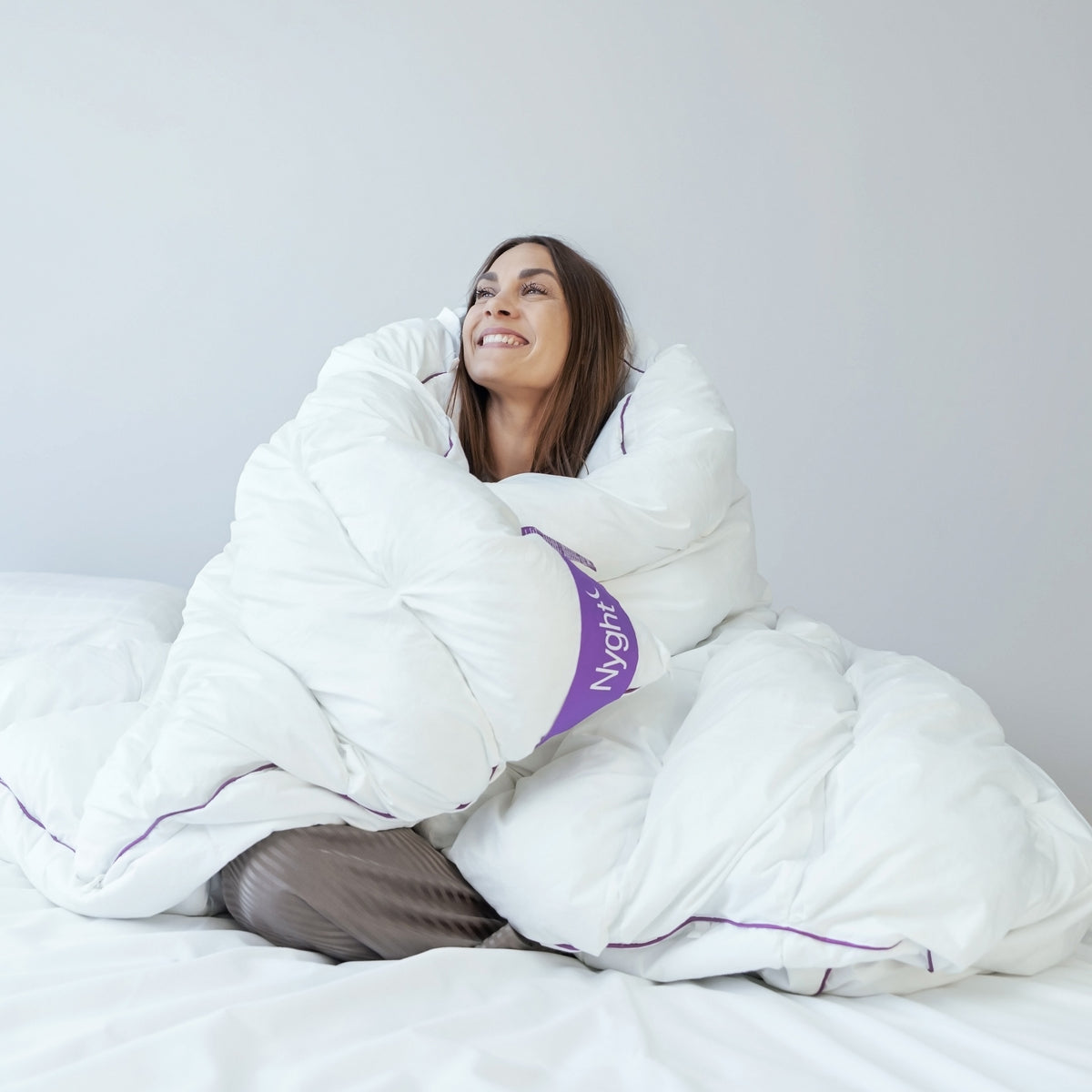 Smilende kvinde svøbt i Hybridduvet i sengen