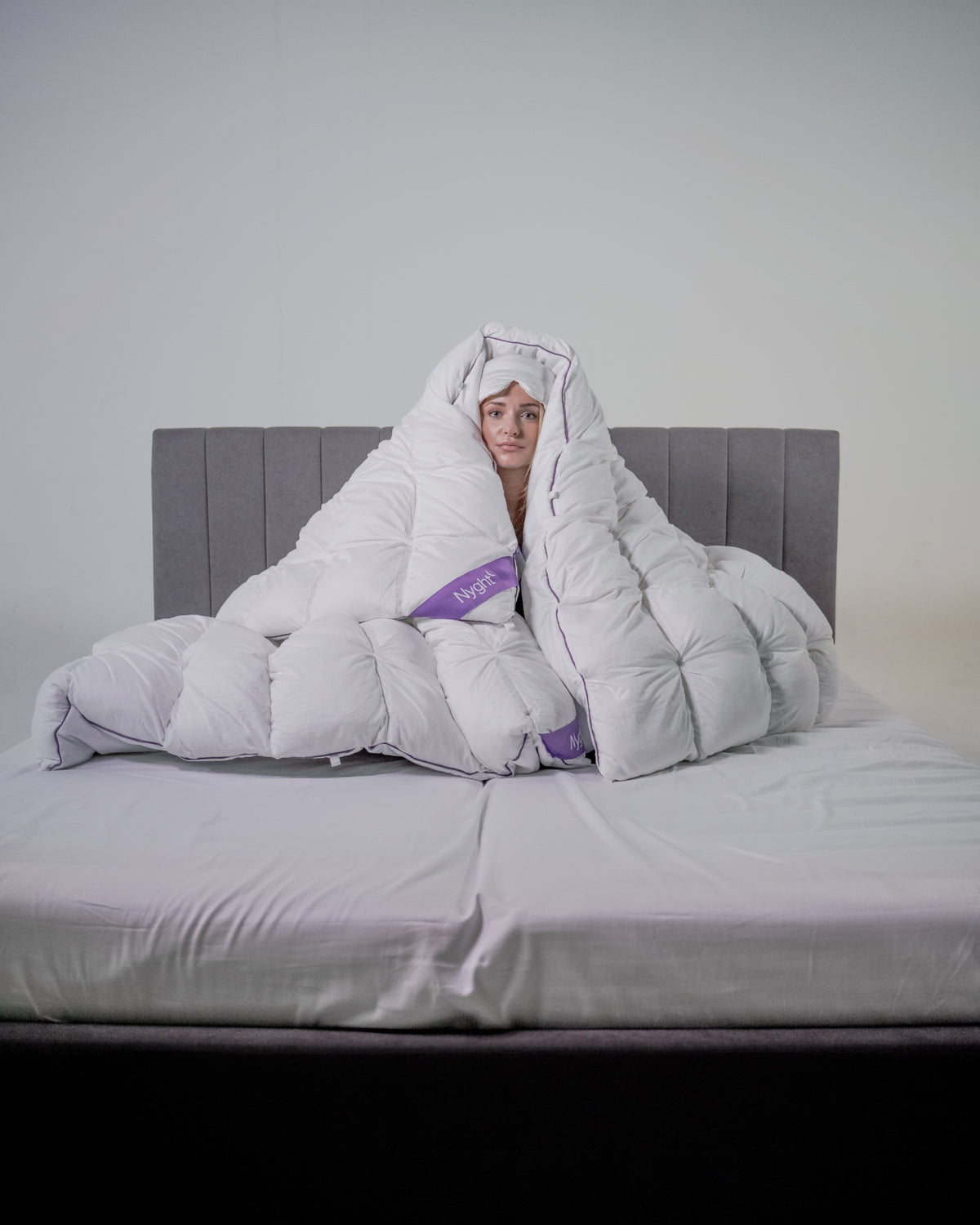 Kvinde svøbt fra top til tå i Hybridduvet på en seng